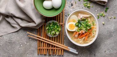 Gri arka planda lezzetli ramen şehriye çorbası, üst manzara.