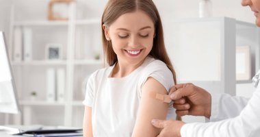 Doktor, klinikteki aşıdan sonra hastanın koluna yama uyguluyor.