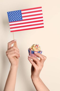 Lezzetli vatansever çörekli kadın eller ve soluk sarı duvarın yanında Amerikan bayrağı. Amerikan Bağımsızlık Günü