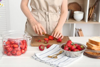 Mutfaktaki masada tatlı çilek reçeli hazırlamak için taze böğürtlen kesen kadın.
