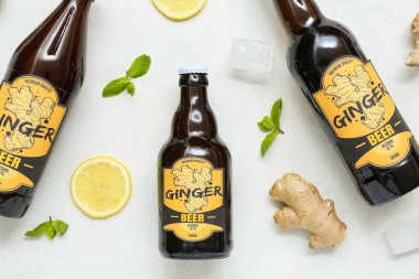 Beyaz zemin üzerinde taze zencefilli bira, nane, limon dilimleri ve buz küpleri olan kompozisyon