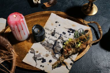 Cadıların sihirli özellikleri, büyü kağıtları, yanan mumlar ve karanlık masa üzerindeki kuru çiçekler, yakın çekim.