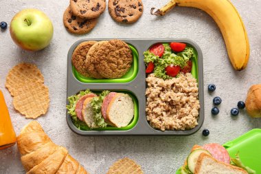Gri arka planda lezzetli yemekler olan beslenme çantaları.