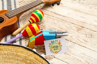 Beyaz ahşap arka planda VIVA MEXICO, marakas ve ukulele yazılı tebrik kartı. Meksika 'nın Bağımsızlık Günü Kutlaması