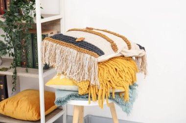 Rafların yanında bir yığın yumuşak yastık ve battaniyeli sandalye.