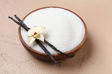 Aromatik vanilya şekeri, çiçek ve bej arka planda çubuklar olan bir kase.