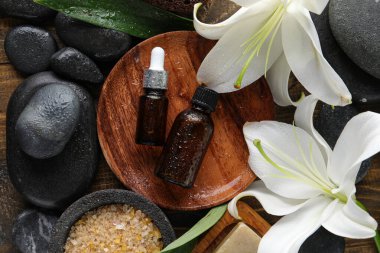 Kozmetik ürünleri şişeleri, spa aksesuarları ve ahşap arka planda zambak çiçekleri olan kompozisyon