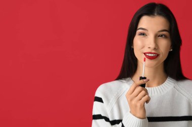 Kırmızı arka planda parlak ruju olan güzel bir genç kadın.