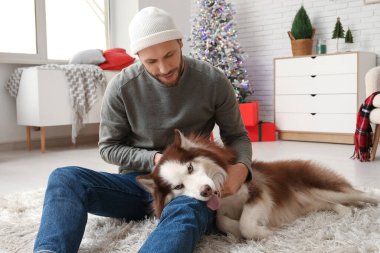 Evde sevimli köpekli yakışıklı bir genç adam.