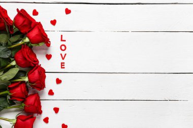 Kırmızı güller, kalpler ve sözcük aşk beyaz ahşap arka planda