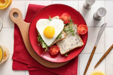 Lezzetli kızarmış yumurta, tost, domates, roka ve açık fayanslı bir bardak meyve suyu.