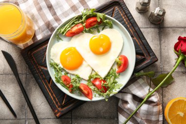 Lezzetli sahanda yumurta, domates ve gri fayanslı bir bardak meyve suyu karışımı.
