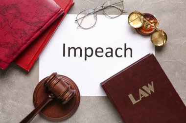 Paper with word IMPEACH, judge gavel, scales of justice and law books on grey grunge background