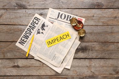 Üzerinde IMPEACH ve ahşap masa üzerinde adalet terazisi yazan gazeteler.