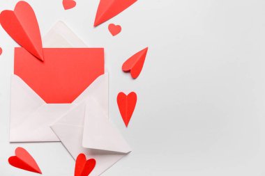 Boş kartlı zarflar ve beyaz arka planda kırmızı kağıt kalpler. Sevgililer Günü kutlaması