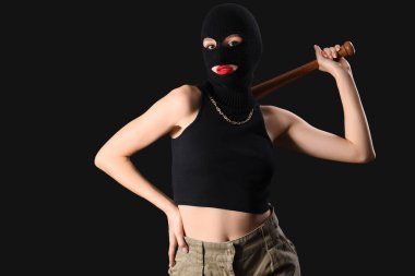 Siyah arka planda beyzbol sopasıyla kar maskeli güzel, genç bir kadın.
