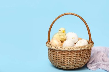 Mavi arka planda Paskalya yumurtası ve tavuk heykelciği olan sepet.