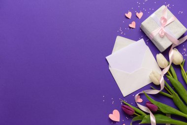 İçinde boş kart, hediye kutusu ve mor arka planda lale çiçekleri olan bir zarf. Uluslararası Kadınlar Günü kutlamaları