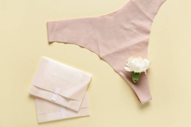 Sarı arka planda karanfil çiçeği ve iç çamaşırı olan adet pedleri.