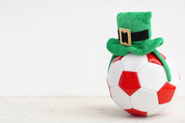 Beyaz grunge arka planında cüce şapkası olan futbol topu. Aziz Patrick Günü kutlaması