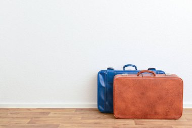 Mavi ve kahverengi eski deri bavullar odada yerde.