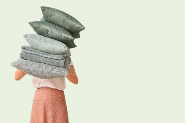 Yastık yığını ve katlanmış, arka planda sıcak ekoseli kadın.