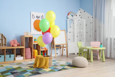 İçinde renkli balonlar ve oyuncaklar olan çocuk odasının içi.