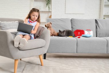 İngiliz kedisi evde ilk yardım çantası ve panosuyla küçük şirin bir kızı ziyaret ediyor.