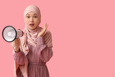 Genç Asyalı Müslüman kadını pembe arka planda megafonla şoke etti. Ulusal Duyulma Günü