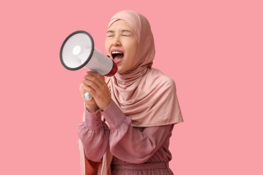Genç Asyalı Müslüman kadın pembe arka planda megafona bağırıyor. Ulusal Duyulma Günü