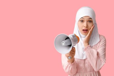 Genç Asyalı Müslüman kadını pembe arka planda megafonla şoke etti. Ulusal Duyulma Günü