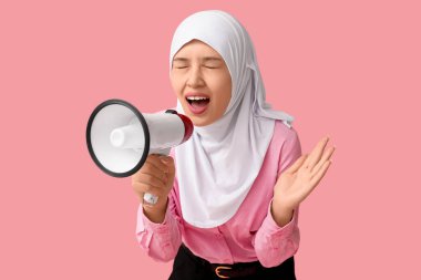 Genç Asyalı Müslüman kadın pembe arka planda megafona bağırıyor. Ulusal Duyulma Günü