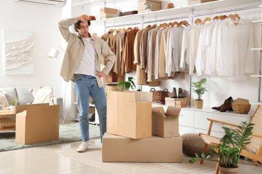 Soyunma odasında kostüm kutuları ve şık giysileri olan yakışıklı, yorgun bir adam.