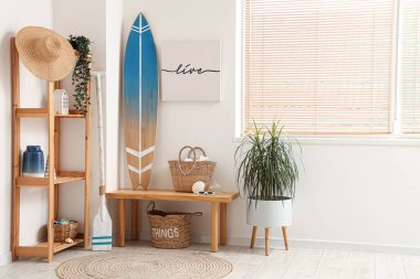 Surfboard, picture, bag and paddle near white wall in room