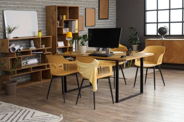 Çalışma yeri, raf üniteleri ve bitkileri olan şık bir ofis.