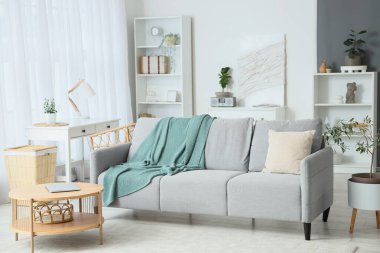 Loş gri kanepe ve dizüstü bilgisayarı ahşap sehpanın üzerinde, aydınlık oturma odasının içinde.