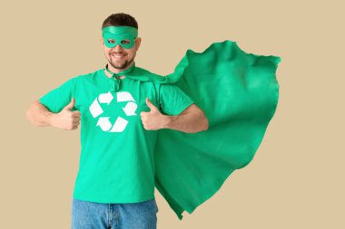 Çevreci süper kahraman gibi giyinmiş genç adam bej arka planda onay veriyor. Ekoloji kavramı