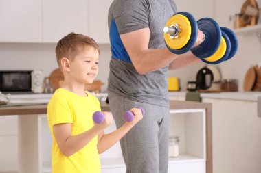 Young man and his little son training with dumbbells at home