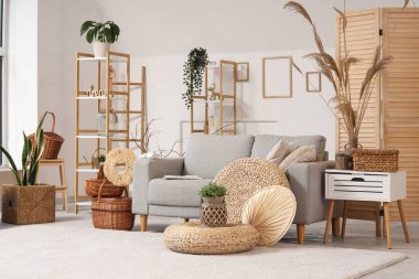 Gri kanepeli, örgülü sepetli, sehpalı ve otlu şık bir oturma odası.