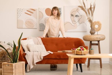 Beyaz oturma odasındaki kahverengi kanepenin yanında güzel bir kadın.