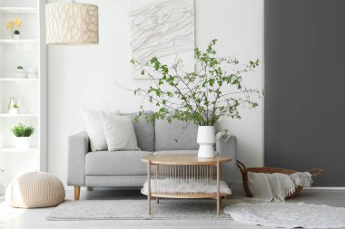 Oturma odasındaki sehpanın üzerinde çiçek açan bir vazo ve rahat bir kanepe.