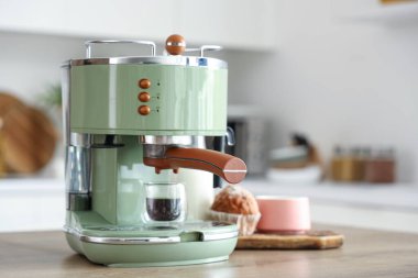Modern kahve makinesi. Mutfaktaki masada bir fincan sıcak espresso ve kek.