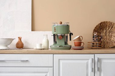 Mutfaktaki masada fincanlar ve bir şişe sütle modern kahve makinesi.