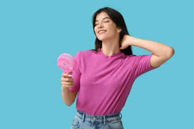 Mavi arka planda mini fanı olan genç bir kadın.