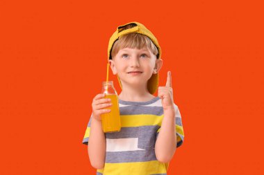 Limonata şişesi turuncu arka plandaki bir şeyi gösteren şirin bir çocuk.