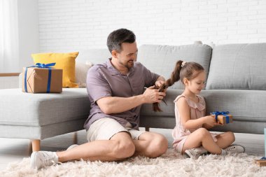 Baba, kızını oturma odasında örüyor. Babalar günü kutlaması.