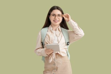 Yeşil arka planda tablet bilgisayarı olan kulaklıklı bir kız öğrenci.