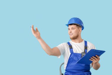 Mavi arka planda panosu olan bir erkek müteahhit.