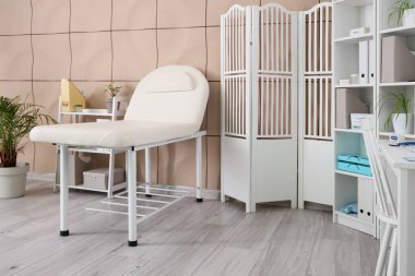 Kanepe, katlanan ekran ve raf üniteleri olan bir tıp bürosu.