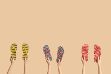 Bej arka planda üç çift çizgili parmak arası terlikli eller.